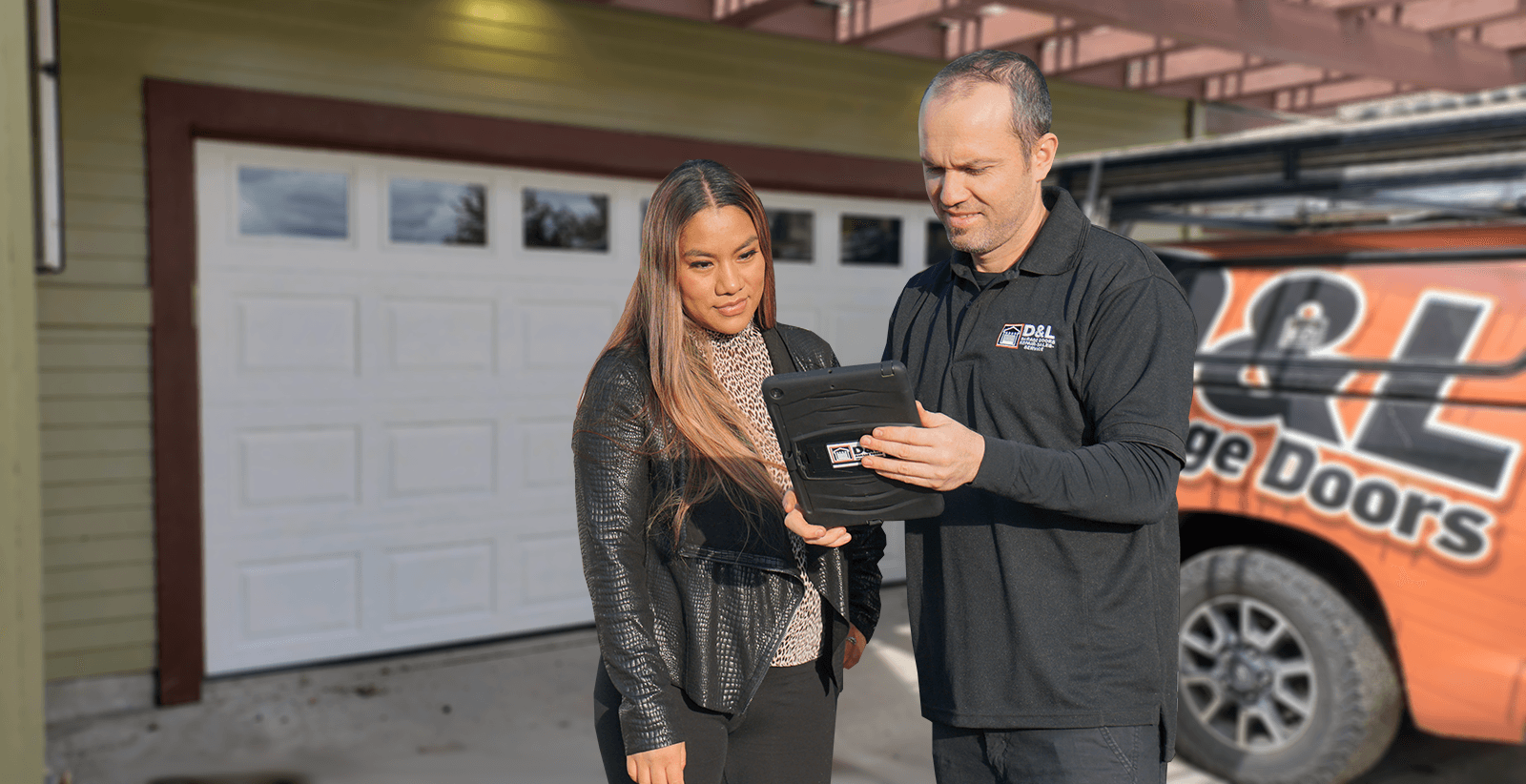 D&L Garage Doors technician consulting with customer in front of branded service truck
